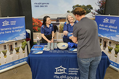 Two Residential Tenancies Authority staff provide tenancy information and resources to a community member at an information booth at the Toowoomba Show 2026.
