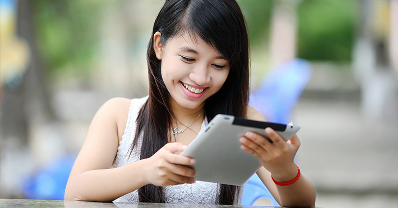 Young lady smiling at tablet