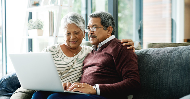 Ethnic couple reading article on laptop