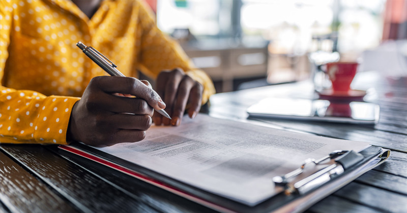 Woman holding pen completing form.