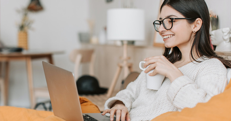 Young woman on lounge with laptop and coffee