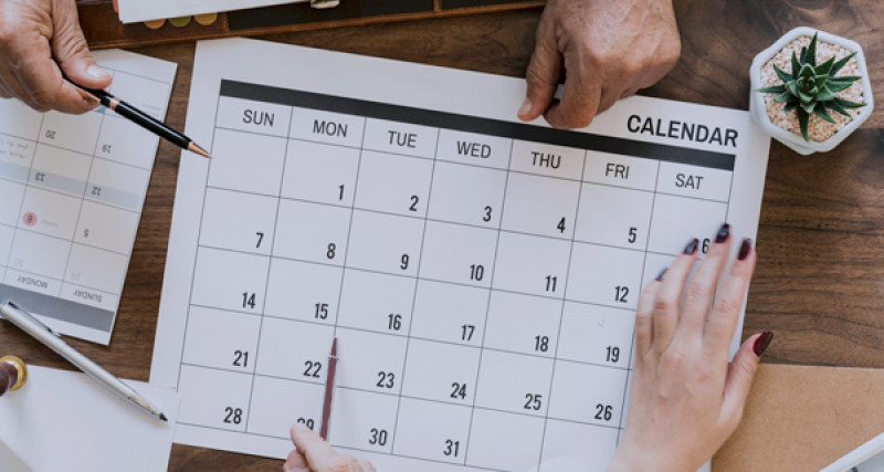 People's hands marking up a calendar