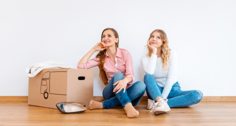 Two men sitting on the floor with a removalist box