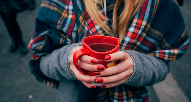 Person with scarf holding coffee