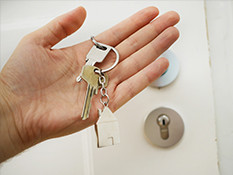 Person holding house keys in front of locked door