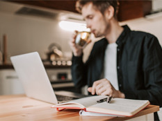 Young man drinking coffee whilst on his laptop