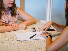 Two women having a discussion on a kitchen bench.