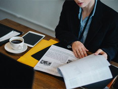 Woman sitting at desk reviewing a large document.